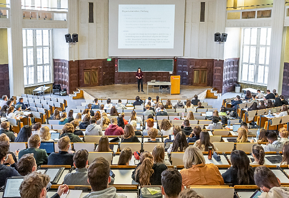Studierende hören einer Dozentin in einem Hörsaal einer Universität zu.
